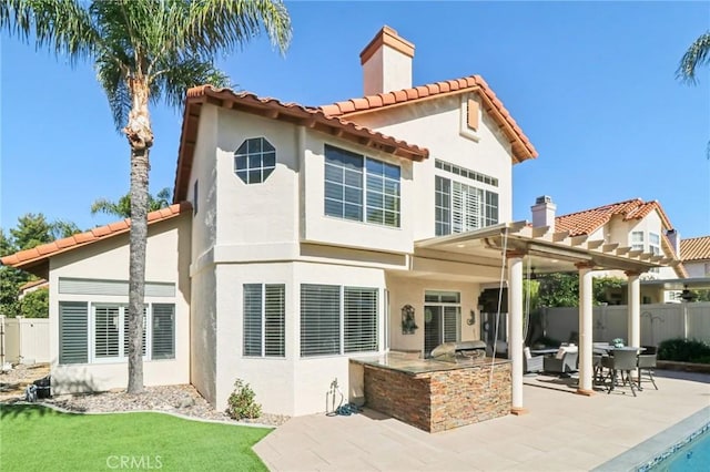 back of property featuring exterior kitchen, fence, a patio, and stucco siding