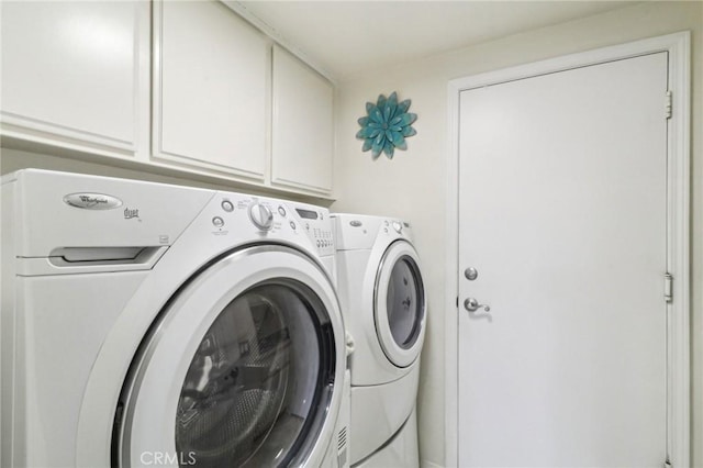 clothes washing area with washing machine and dryer and cabinet space