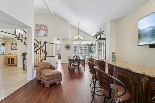 interior space with high vaulted ceiling, hardwood / wood-style flooring, a dry bar, and stairs