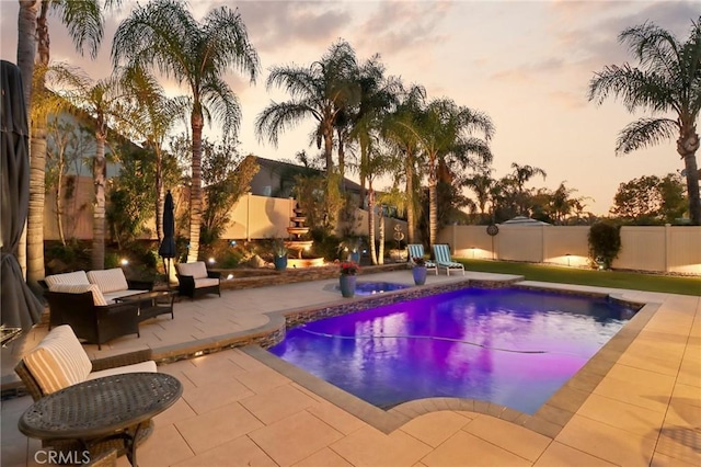 pool at dusk featuring a patio area, a fenced backyard, and a fenced in pool