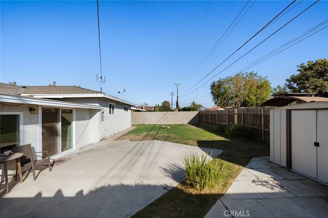 view of yard with a patio area, an outdoor structure, a fenced backyard, and a storage shed