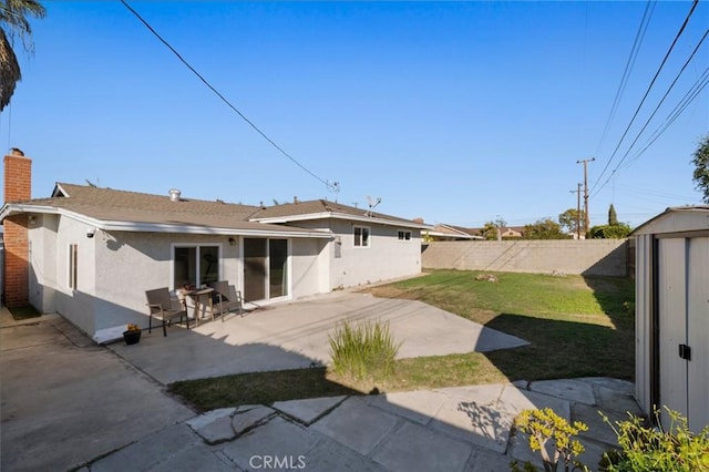 back of property featuring a yard, a patio area, a shed, an outdoor structure, and stucco siding