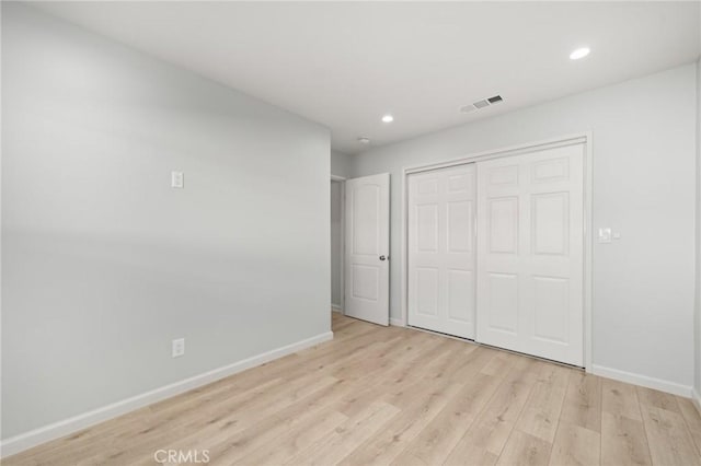 unfurnished bedroom with light wood finished floors, baseboards, visible vents, a closet, and recessed lighting