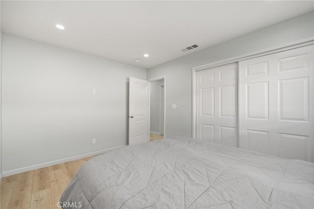 bedroom with light wood finished floors, visible vents, baseboards, a closet, and recessed lighting