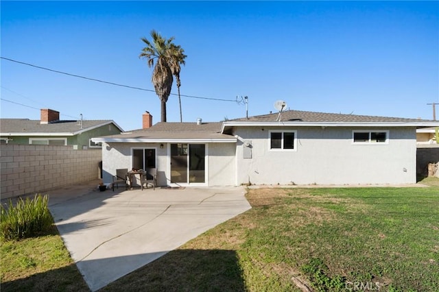 rear view of house featuring a lawn, a patio area, fence, and stucco siding