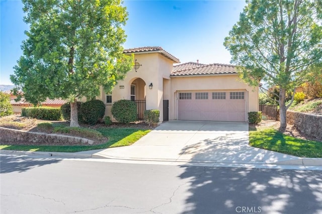 mediterranean / spanish house featuring a garage, fence, a tile roof, driveway, and stucco siding