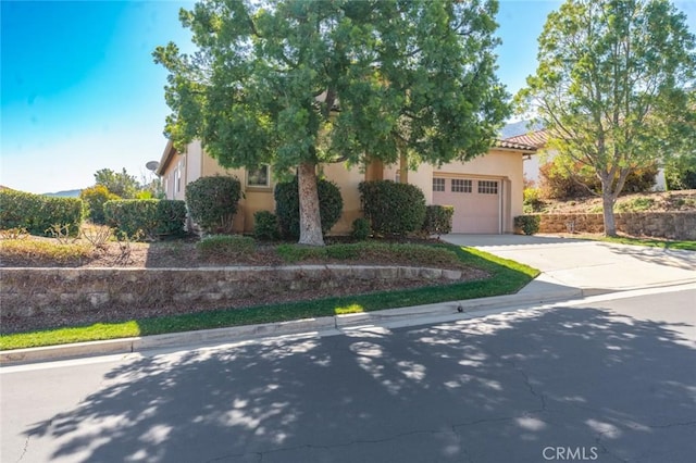 obstructed view of property featuring a garage, driveway, a tiled roof, and stucco siding