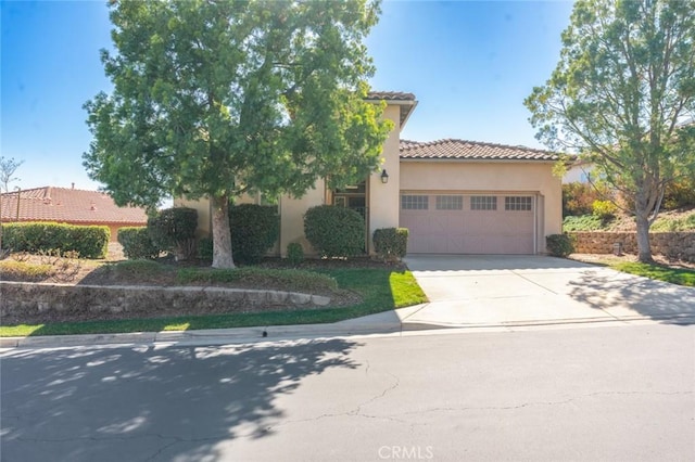 view of front facade with driveway, stucco siding, a garage, and a tiled roof