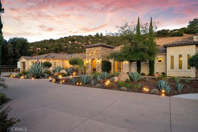 mediterranean / spanish-style home featuring a tile roof, driveway, and stucco siding