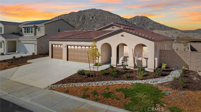 view of front of home featuring a mountain view, a garage, a tiled roof, concrete driveway, and stucco siding