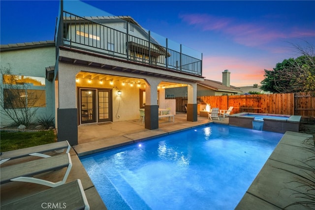 exterior space featuring a fire pit, a fenced backyard, a balcony, and stucco siding