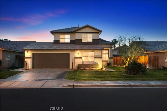 view of front facade with fence, concrete driveway, a yard, a tiled roof, and stucco siding