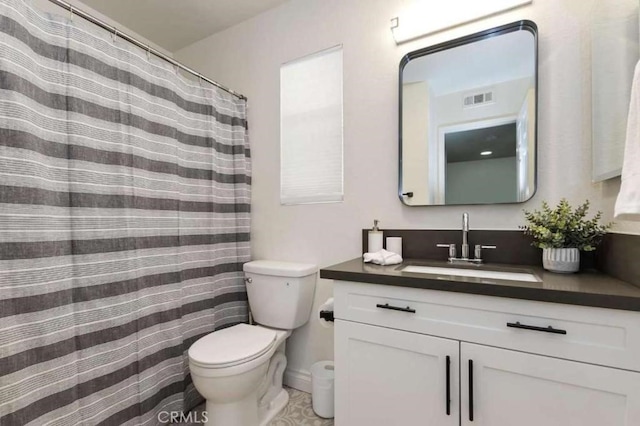 bathroom with toilet, vanity, and visible vents