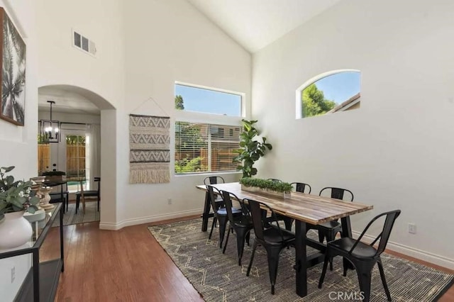 dining space featuring arched walkways, visible vents, an inviting chandelier, dark wood-type flooring, and baseboards