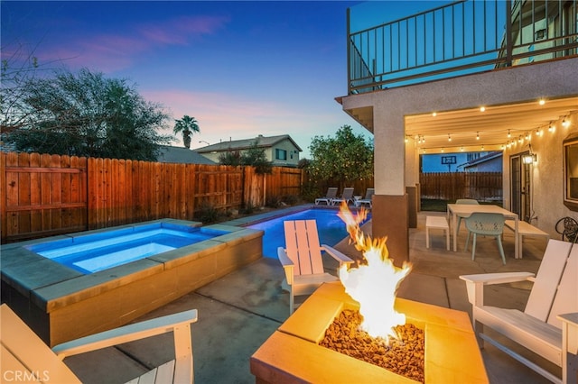 pool at dusk with a fenced in pool, a fenced backyard, a fire pit, and an in ground hot tub