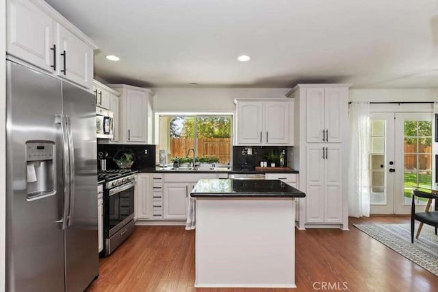 kitchen with dark wood-style floors, tasteful backsplash, appliances with stainless steel finishes, white cabinetry, and a sink