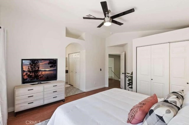 bedroom featuring baseboards, arched walkways, a ceiling fan, dark wood finished floors, and vaulted ceiling