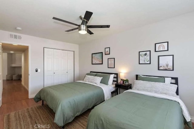 bedroom featuring a closet, visible vents, ceiling fan, wood finished floors, and baseboards