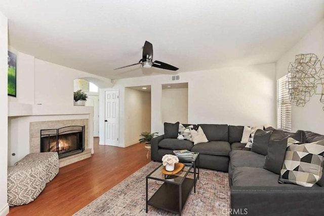 living room with visible vents, a ceiling fan, a tile fireplace, wood finished floors, and a wealth of natural light