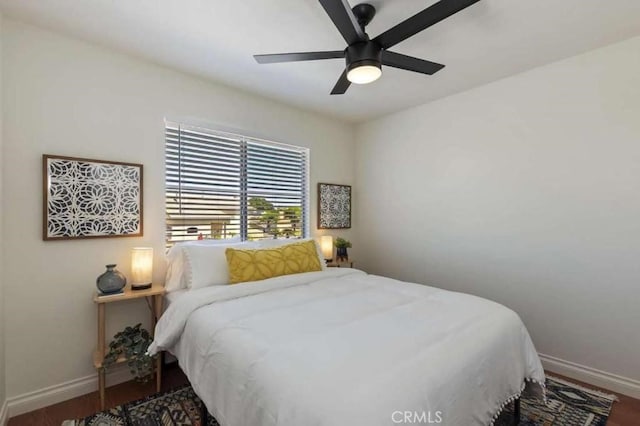 bedroom with dark wood-style floors, ceiling fan, and baseboards