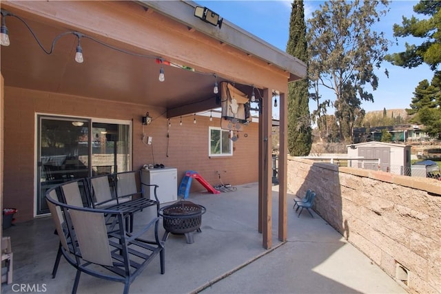 view of patio with washer / clothes dryer, fence, and a fire pit