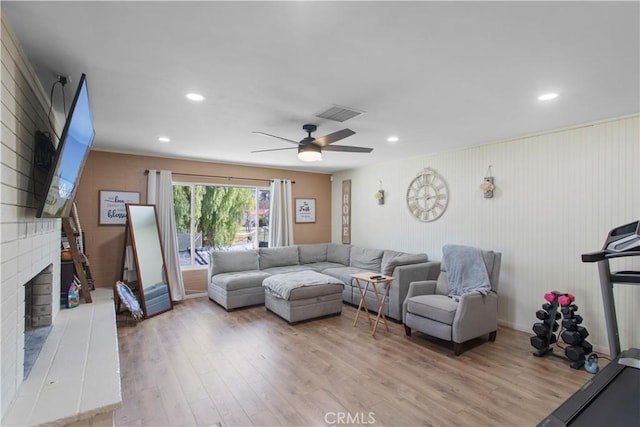 living room with a brick fireplace, visible vents, wood finished floors, and recessed lighting