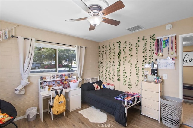 bedroom with a ceiling fan, visible vents, and wood finished floors