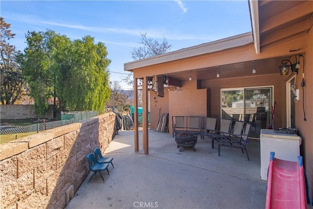 view of patio with an outdoor fire pit and fence