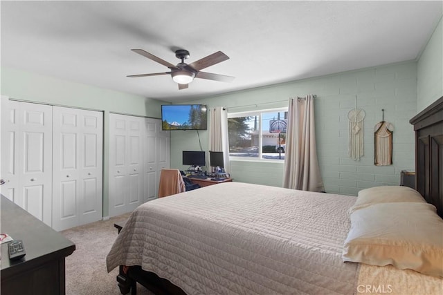 carpeted bedroom featuring multiple closets and ceiling fan