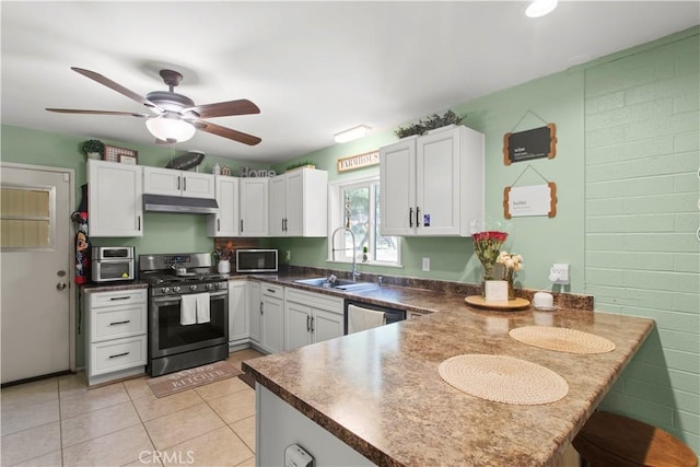 kitchen featuring under cabinet range hood, a peninsula, a sink, appliances with stainless steel finishes, and dark countertops