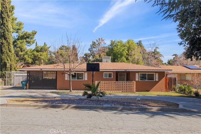 ranch-style home with driveway, fence, and a gate