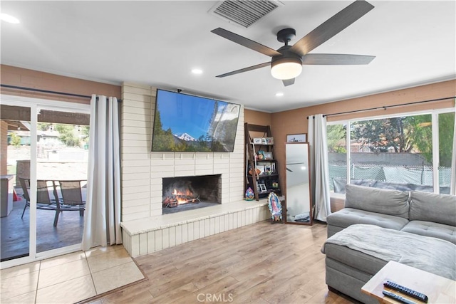 living room with recessed lighting, visible vents, light wood-style floors, a brick fireplace, and ceiling fan