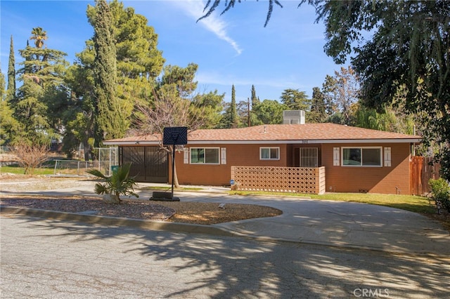 ranch-style home with driveway, brick siding, fence, and a gate