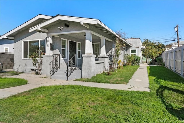 bungalow featuring a front yard, fence, and stucco siding