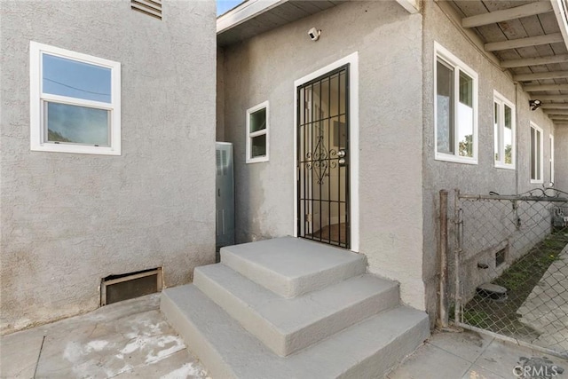 property entrance featuring fence and stucco siding