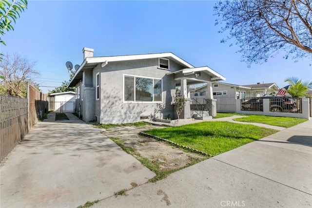 bungalow with a fenced front yard, a gate, a chimney, and stucco siding