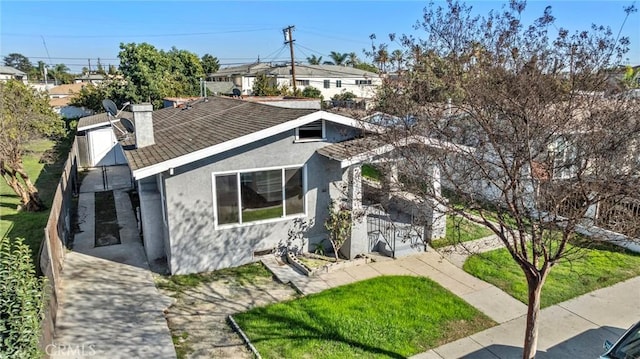 exterior space with a front lawn, a chimney, and stucco siding