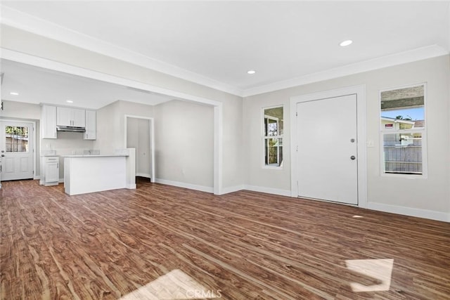 unfurnished living room with crown molding, baseboards, wood finished floors, and recessed lighting