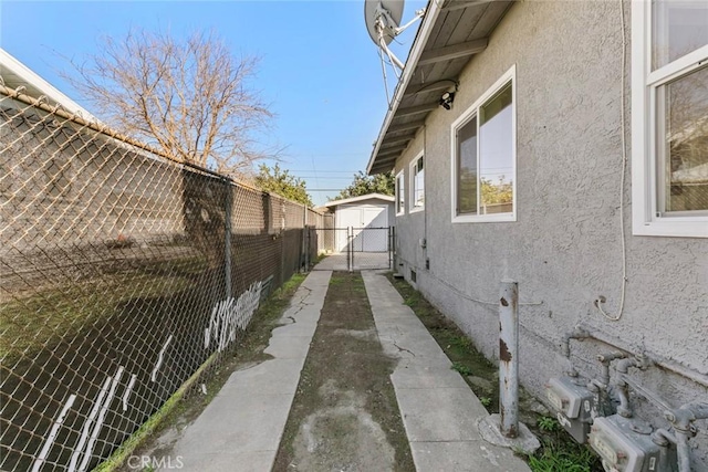 view of side of home featuring a gate, fence, and stucco siding