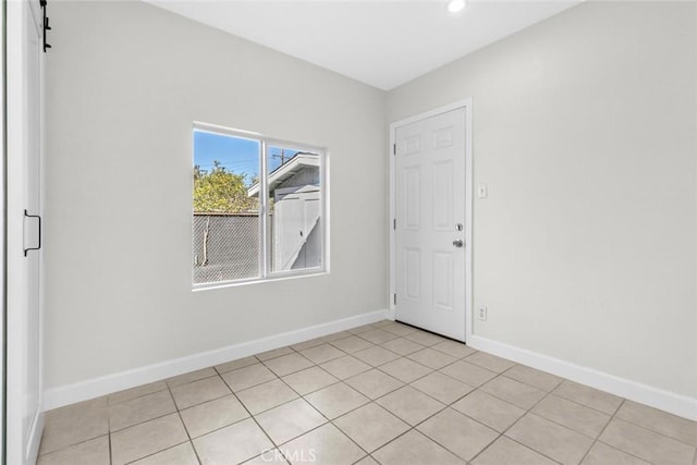 unfurnished room featuring recessed lighting, a barn door, baseboards, and light tile patterned flooring