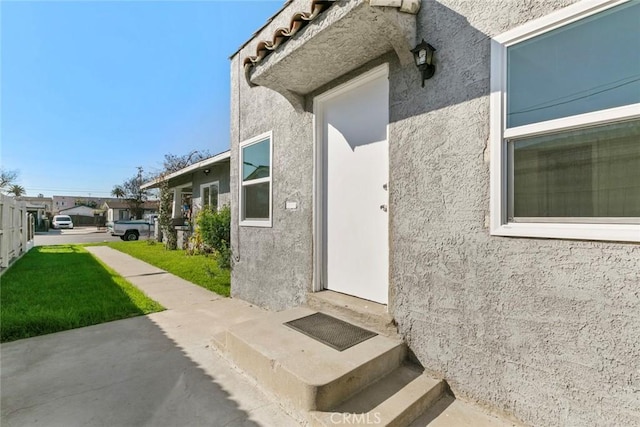 doorway to property with a yard and stucco siding