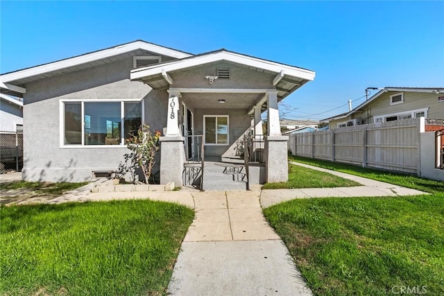 view of front of house with a front lawn, fence, and stucco siding