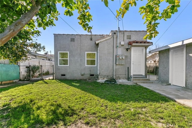 rear view of house with crawl space, a yard, fence, and stucco siding