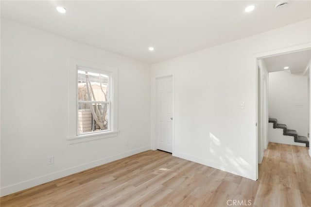 spare room with stairway, recessed lighting, light wood-style flooring, and baseboards