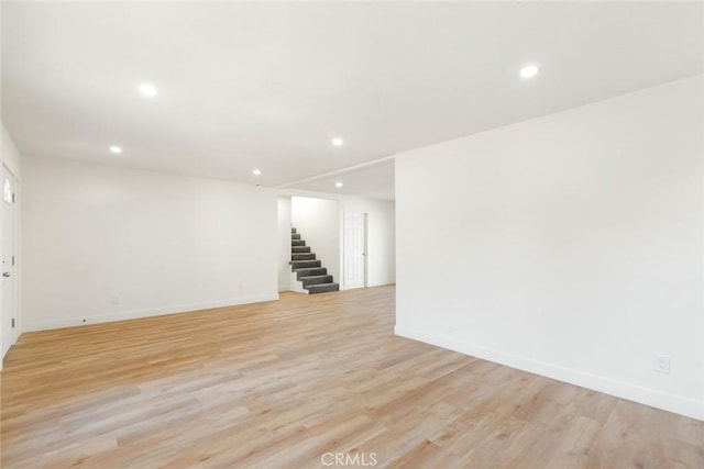 below grade area featuring light wood-type flooring, baseboards, recessed lighting, and stairs