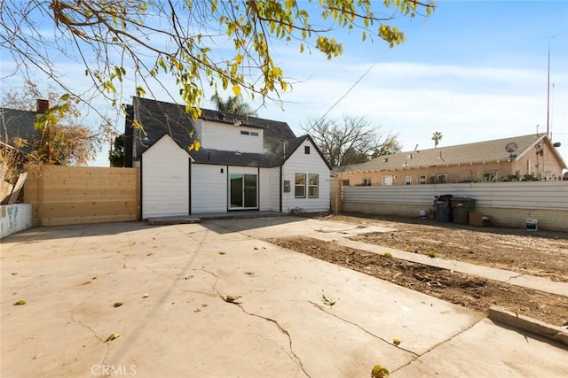 rear view of house with driveway, a patio area, and fence