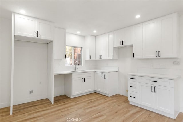 kitchen featuring light wood-style flooring, recessed lighting, a sink, white cabinetry, and light countertops