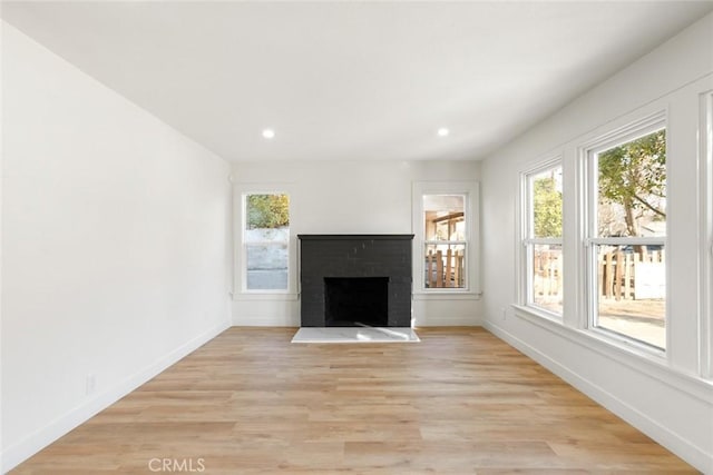 unfurnished living room featuring a brick fireplace, light wood-style flooring, baseboards, and recessed lighting