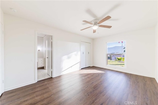 empty room featuring ceiling fan, wood finished floors, and baseboards