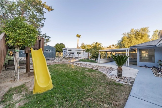 view of yard with a patio area, a playground, and fence